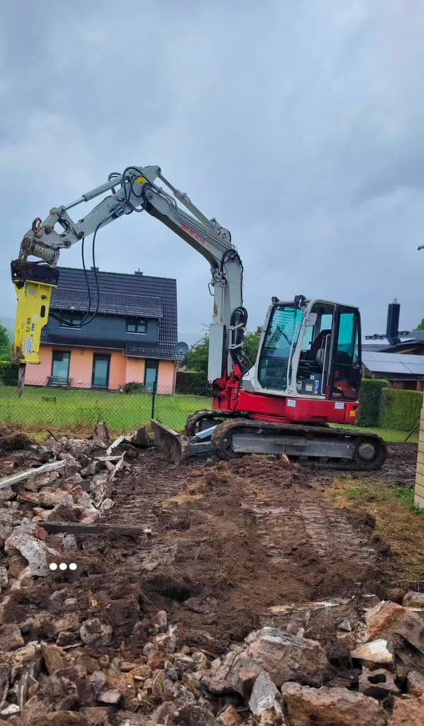 Bagger mit Hydraulikhammer bei Abbruch- und Räumarbeiten auf einem Grundstück im Wohngebiet