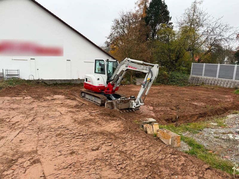 Bagger beim Abtragen und Planieren einer Gewerbefläche neben einem Betriebsgebäude in der Region Bergstraße–Odenwald