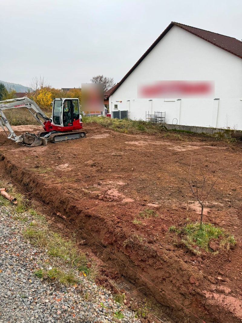 Großflächiger Aushub auf einem Firmengelände: Bagger auf der abgetragenen Fläche neben dem Marktgebäude