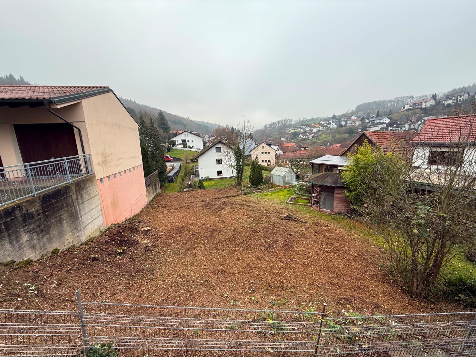 Nach der Rodung freigeräumtes Grundstück zwischen Wohnhäusern mit Blick ins Tal im Odenwald